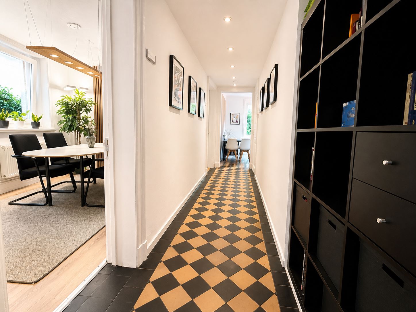 Flur mit Schachbrettboden, Bildern an der Wand und Regal
