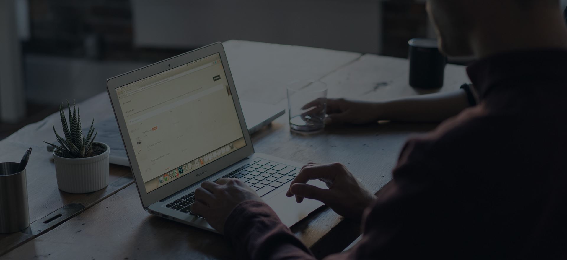 Person arbeitet am Laptop an einem Holztisch